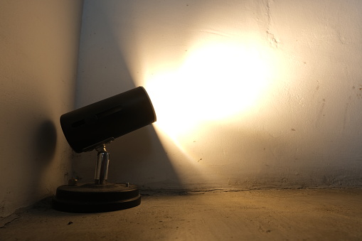 Vintage desk lamp casting bright light on a textured wall, perfect for interior design and decoration themes.