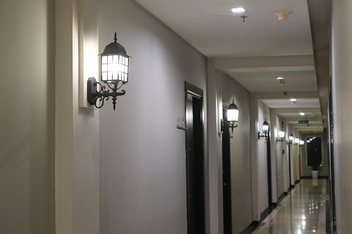 Classic hallway with elegant wall-mounted lanterns and doors, hotel interior design.