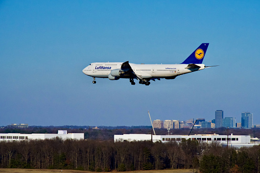 Chantilly, Virginia, USA - February 19, 2024: The Reston Town Center can be seen in the background as a Lufthansa Boeing 747-830 flight enroute from Frankfurt, Germany, prepares to land at Washington Dulles International Airport.