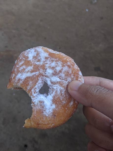 istock Hand holding a donut with powdered sugar that has bite marks 2047021918
