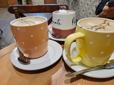 A selection of crafted cappuccinos and lattes in colorful polka dot mugs on a cafe table