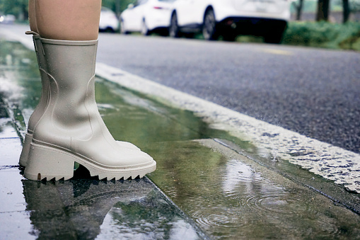 Woman wearing rain boots standing on the street with rain puddles