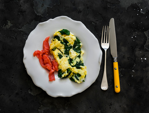 Spinach omelette and lightly salted salmon - delicious breakfast, brunch on a dark background, top view