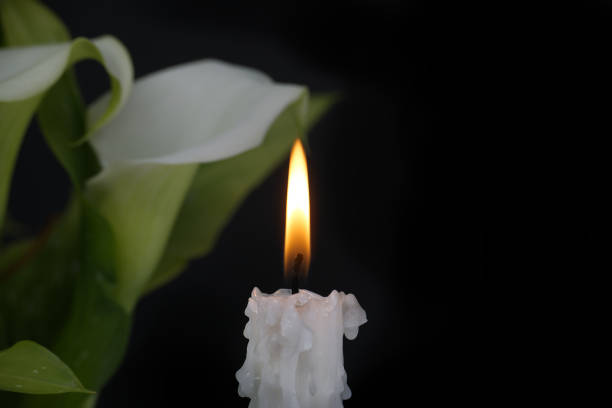 istock White calla lily flowers and burning wax candle in darkness 2047046113