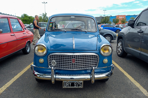 Buenos Aires, Argentina - Feb 25, 2024: Old blue 1960 Fiat 1100 four door sedan at a classic car show in a parking lot. Front view. Grille