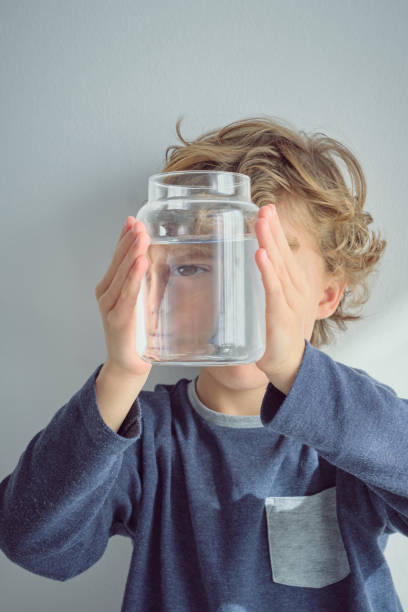istock Kid covering face with jar of water 2047081369