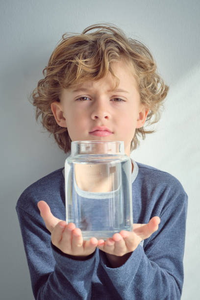 istock Cute boy holding glass jar with water 2047081376