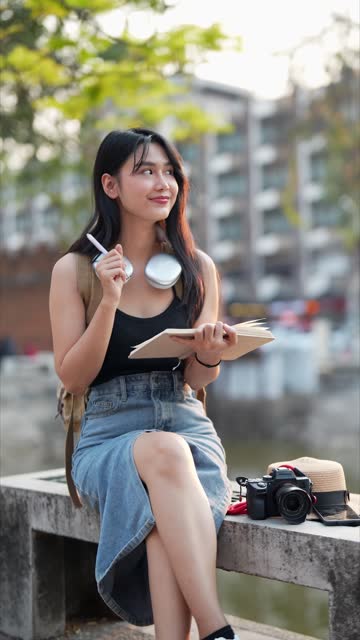 Asian female traveler using a diary and relaxing at a tourist spot in a northern province of Thailand