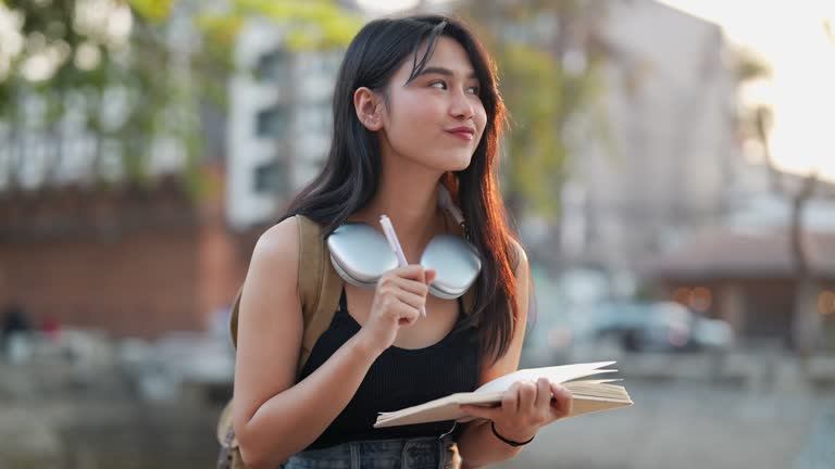 Asian female traveler using a diary and relaxing at a tourist spot in a northern province of Thailand