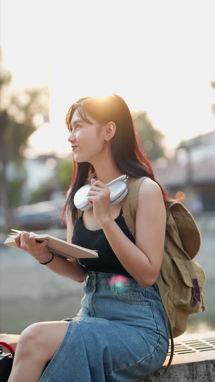 Asian female traveler using a diary and relaxing at a tourist spot in a northern province of Thailand