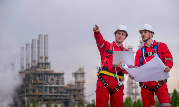 istock Engineer survey team wear uniform and helmet stand workplace checking blueprint project , radio communication and engineer box inspection work construction site with oil refinery background. 2047186462