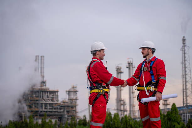 istock Engineer survey team wear uniform and helmet stand workplace checking blueprint project , radio communication and engineer box inspection work construction site with oil refinery background. 2047188973