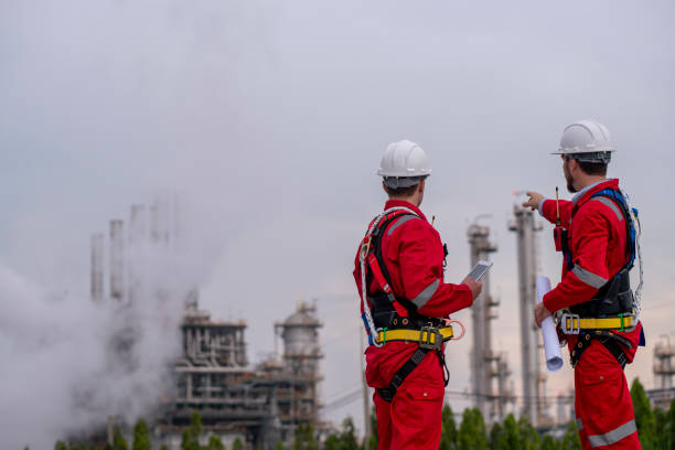 istock Engineer survey team wear uniform and helmet stand workplace checking blueprint project , radio communication and engineer box inspection work construction site with oil refinery background. 2047188974