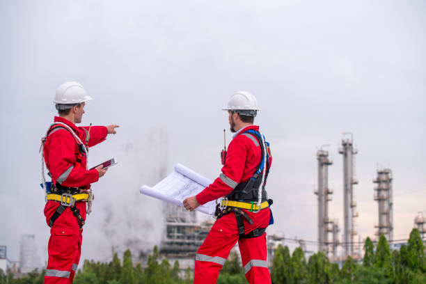 istock Engineer survey team wear uniform and helmet stand workplace checking blueprint project , radio communication and engineer box inspection work construction site with oil refinery background. 2047190036