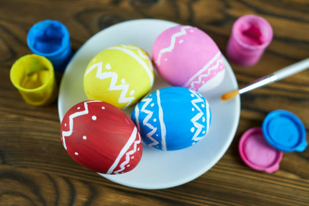 Easter eggs painted in bright colors with a brush on a wooden background. Master class for children.