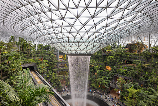 Singapore - January 7, 2024: Singapore Jewel Changi Airport. The Singapore Jewel Rain Vortex is the largest indoor waterfall in the world located inside the Jewel Changi at the Airport in Singapore. Singapore Monorail Railroad Track in the Foreground.