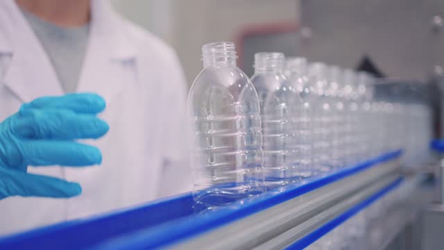 Industrial processing bottles of mineral water orders at warehouse. Shot of manufacturing stock of transparent plastic water bottles, water bottle factory industry concept.