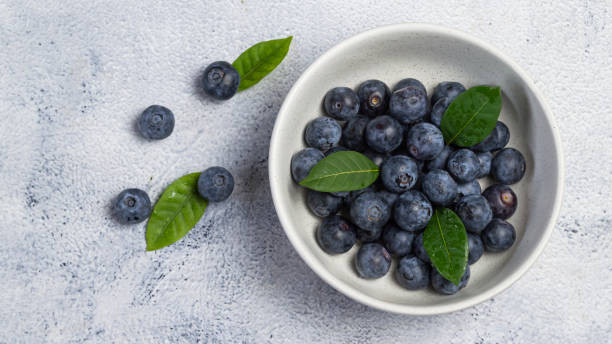 istock Fresh purple blueberries in a white cup 2047223451