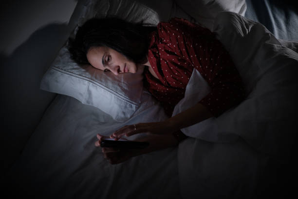 istock Hispanic woman scrolling smartphone in darkness 2047228196