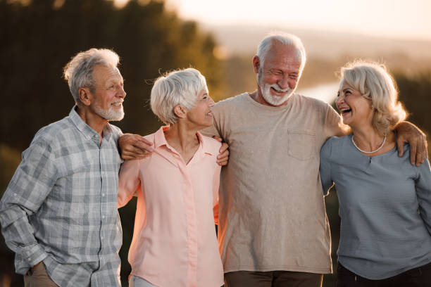 istock Cheerful mature friends talking while walking embraced in nature. 2047274954