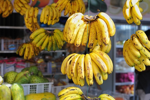 bananas hanging for sale in minimarket, bokeh background