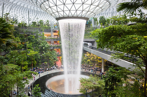 Singapore - January 7, 2024: Singapore The Jewel Changi Airport. The Singapore Jewel Rain Vortex is the largest indoor waterfall in the world located inside the Jewel Changi Airport in Singapore. Singapore Airport Monorail Railway Track on the right through the huge Jewel Changi.