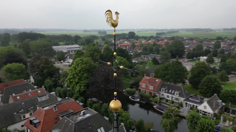 Aerial view orbiting ornate metal cockerel weather vane lightning conductor cross overlooking charming Dutch village