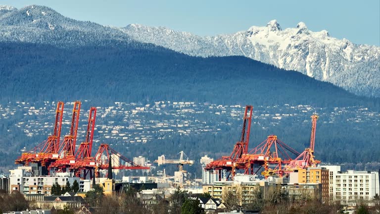 Port Cranes At Vancouver Harbour With Grouse Mountains In Background. British Columbia, Canada. drone pan shot