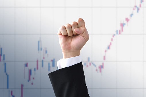 Male fist raised in front of stock chart background