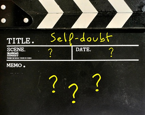 Movie slate with handwriting SELF-DOUBT and lots of question mark - lack of confidence regarding yourself and your abilities - imposter syndrome with work or relationships