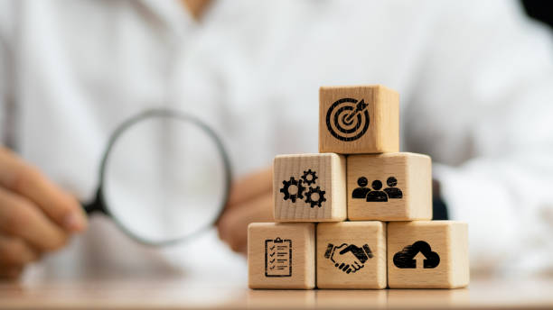 istock Hand touching and push target board which printing on wooden cube block on mechanical gear and lightbulb icon for creative and set up business objective target goal concept. 2047415220