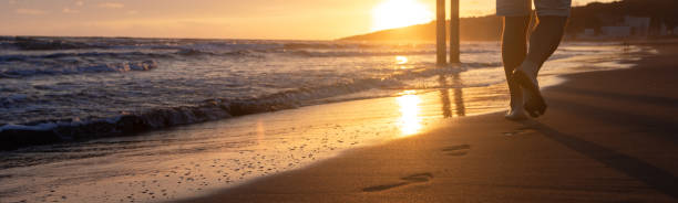 istock Banner incoming waves on the sandy beach at sunset. A sunny path. Bare footprints 2047415739