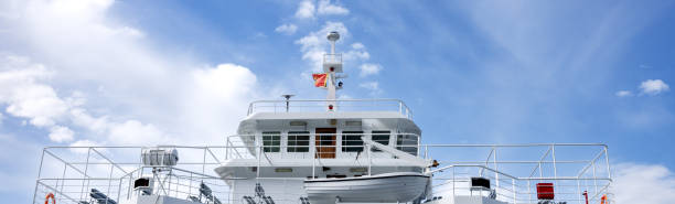 istock banner upper deck on the white ferry. A mast with a flag. Blue sky with white fluffy clouds. Montenegro 2047423525
