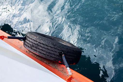mooring tire on board the white ferry against the background of sea water. View from above