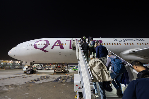 Doha, Qatar - February 26, 2024 : Passengers board a Qatar Airways Boeing 777-300ER at the Hamad International Airport in Doha, Qatar.