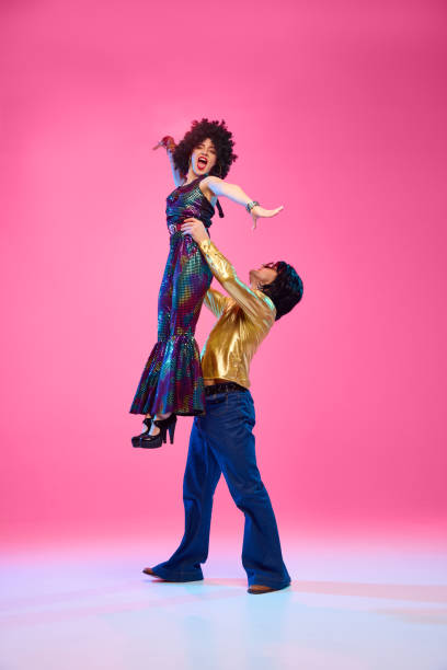 istock To rhythm of dance. Talented couple, dance partners in dynamic disco pose against gradient pink studio background. 2047443528