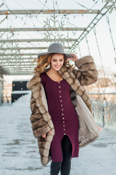 mujer morena de pie en la calle de la ciudad de nieve con sombrero y abrigo de piel - russian culture fashion model hat sensuality fotografías e imágenes de stock