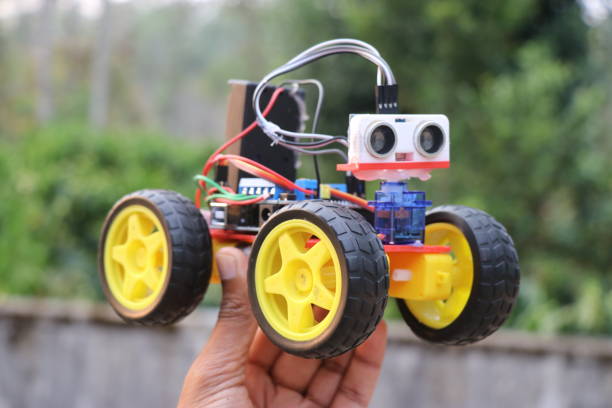 istock Obstacle avoiding car held in the hand. Robotic car equipped with ultrasonic sensor to sense any obstacles 2047463769