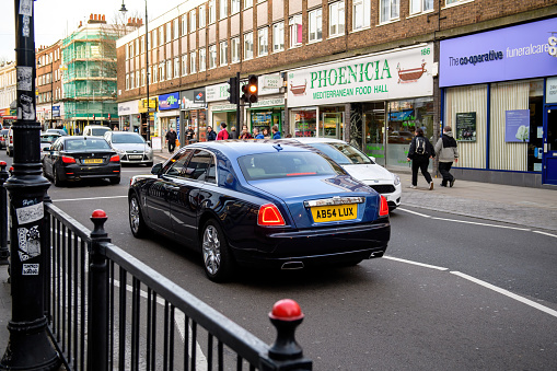 London, United Kingdom - Mar 9, 2017: Rear view of blue luxury Rolls-Royce car driving on Kentish Town Rd street next to Phoencia Mediterranean food hall