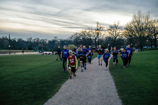 London, United Kingdom - Mar 9, 2017: Group of friends sports team participating at a group workout in Hyde Park central London at dusk