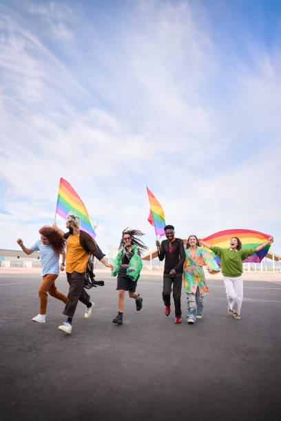 istock Group happy LGBT people walking down street with rainbow flags under clear sky 2047487853