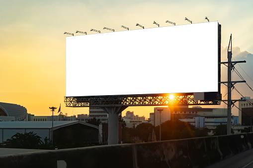Blank billboard at twilight for advertisement. Blank billboard advertising erected outside against a cityscape,copy space for text. Advertisement or Corporate publicity label and business concept.