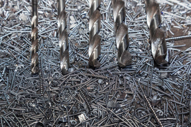 Drill bits for drilling steel lie on steel shavings close-up.