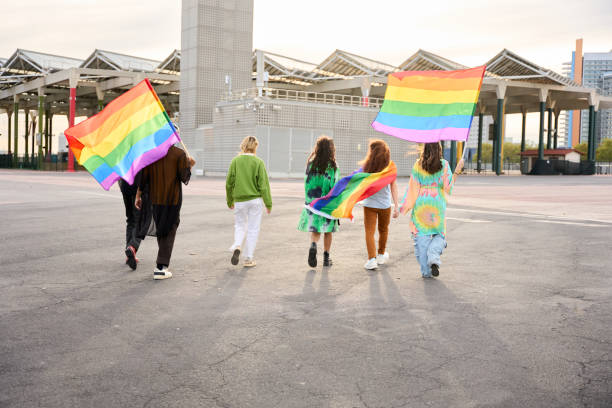 istock Group happy LGBT people walking down street with rainbow flags under clear sky 2047562457