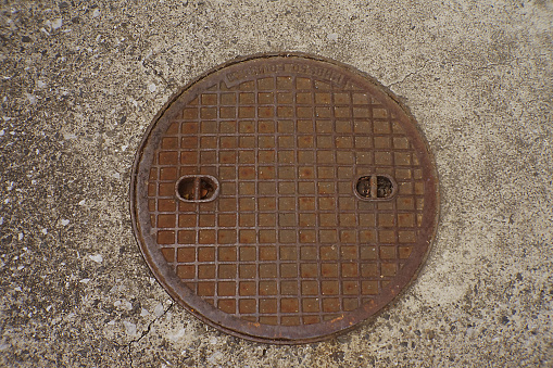 A photo taken from directly above of a manhole that has rusted due to exposure to the wind and rain. Photo data: February 29, 2024, Tokyo. Setagaya Ward, a certain residential area, Japan.