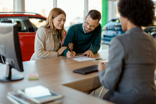 istock Customers Signing Documents at Car Showroom 2047619354
