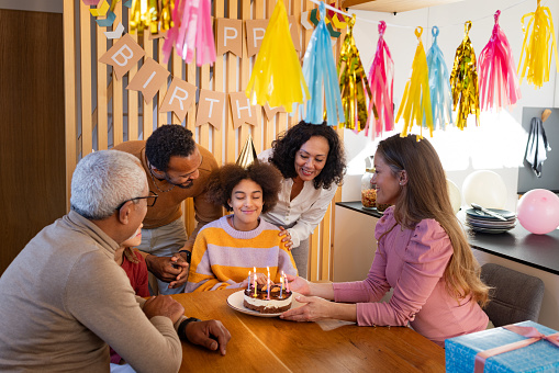 Diverse family celebrating a birthday of a 12 year old girl at home.