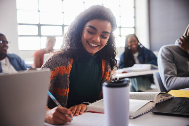 istock Smiling young female college student taking notes during a class at school 2047695219