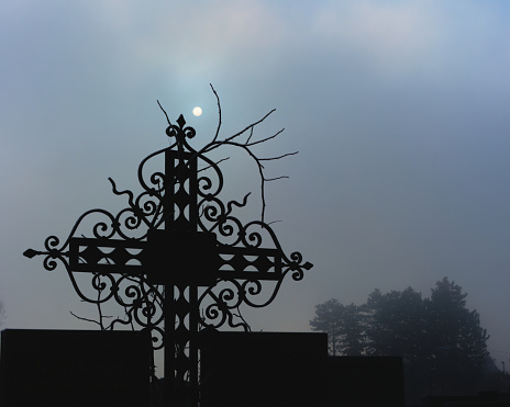 The Sun illuminating a cross in misty sky, Mirogoj Cemetery, Zagreb, Croatia.