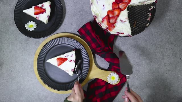 woman serving a strawberry cake or Fraisier  in french language on black plate